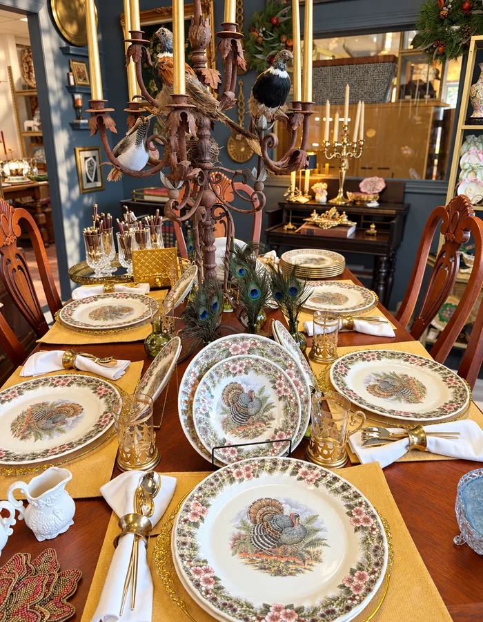 A dining table set with turkey transferware plates and gold placemats